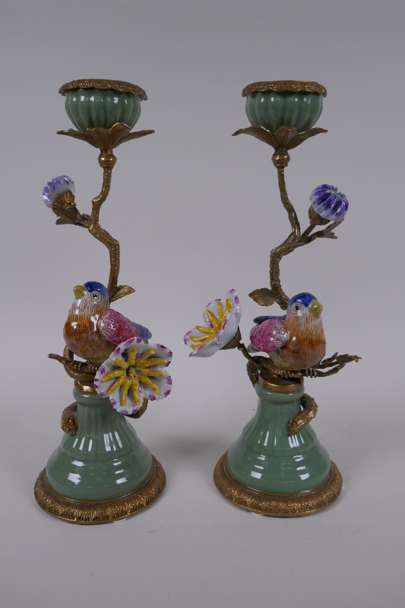 A pair of polychrome porcelain and gilt metal candlesticks decorated with birds and flowers, 29cm