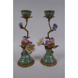 A pair of polychrome porcelain and gilt metal candlesticks decorated with birds and flowers, 29cm