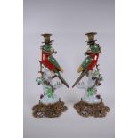 A pair of polychrome porcelain and gilt mounted candle sticks in the form of a parrot perched on a