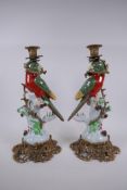 A pair of polychrome porcelain and gilt mounted candle sticks in the form of a parrot perched on a