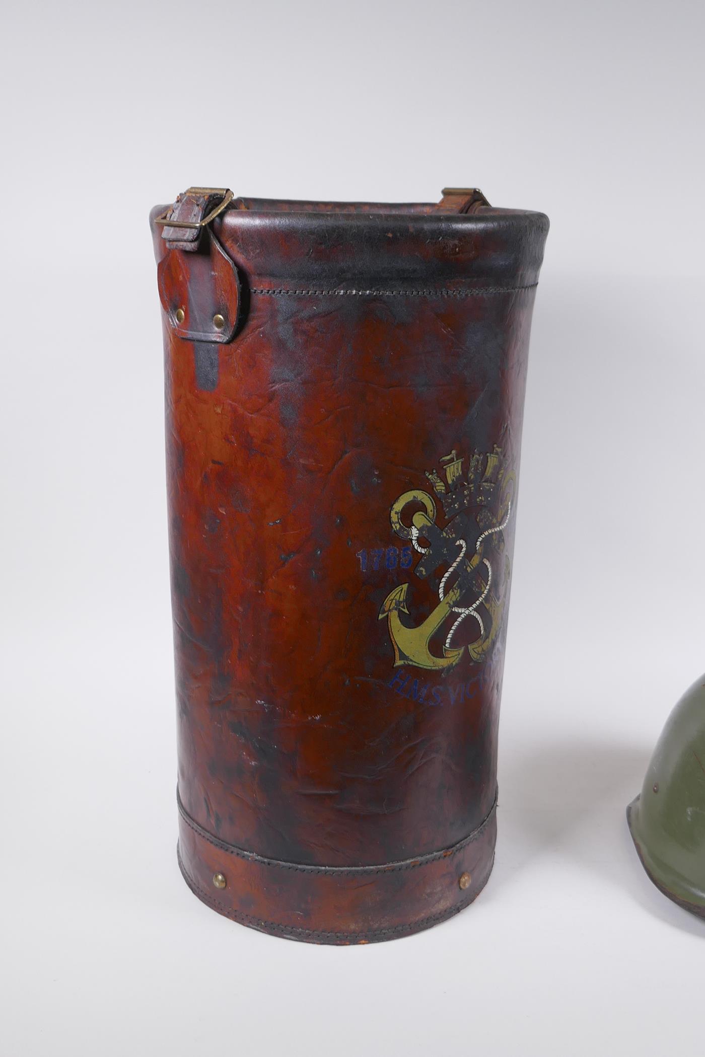 A vintage leather shell case decorated with a later applied armorial crest, and a steel military - Image 2 of 5