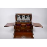 A Victorian oak and silver plated three bottle tantalus, opening to reveal fitted compartments,