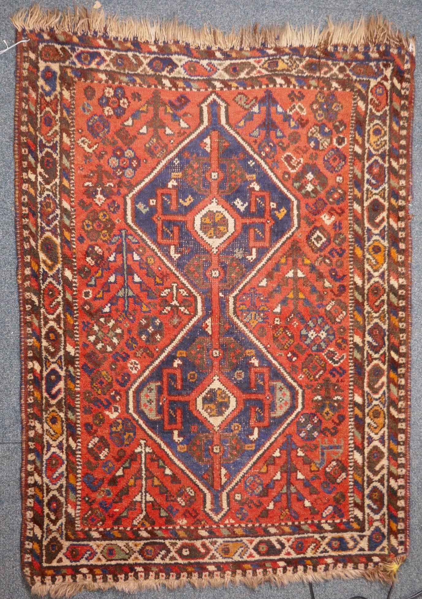 An antique Persian wool rug, with twin blue ground medallions on a tomato field, 124 x 92cm - Image 2 of 4