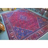 A claret and blue ground Persian Joshaghan tribal carpet with traditional medallion design,