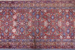 A hand woven red ground Persian Hamadan nomadic runner with an allover floral design, 102 x 310cm
