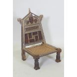 An antique Indian Pidha low chair with folding back, brass and iron mounts and webbed seat