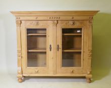 A C19th continental pine bookcase with two glazed door with applied fluted columns and lion mask