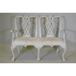A painted Chippendale style two seater settee, with pierced back and carved decoration, raised on