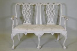 A painted Chippendale style two seater settee, with pierced back and carved decoration, raised on