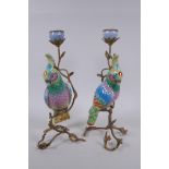 A pair of gilt metal and porcelain candlesticks in the form of a brightly enamelled parrot perched