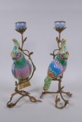 A pair of gilt metal and porcelain candlesticks in the form of a brightly enamelled parrot perched