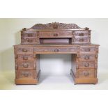 A Victorian oak nine drawer pedestal desk with mask carved handles, inset leather top and upper