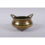 An antique Chinese polished bronze censer with two phoenix eye handles and tripod supports,