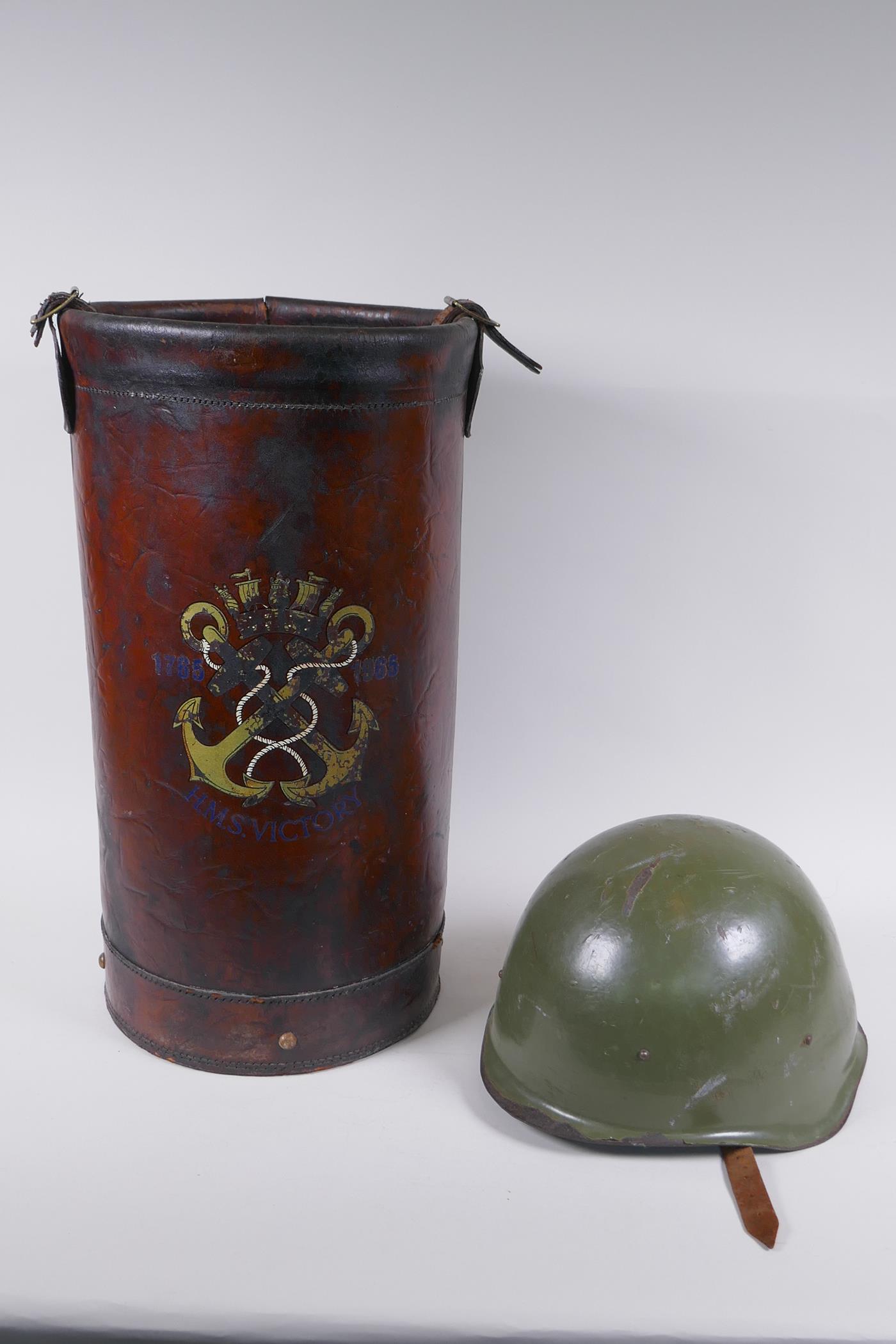 A vintage leather shell case decorated with a later applied armorial crest, and a steel military