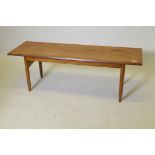 A mid century teak coffee table, raised on tapering supports united by shaped end stretchers, 40 x