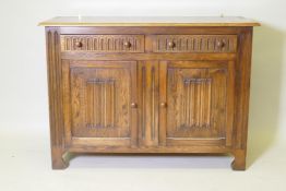 A mid century oak dresser with dome shaped upper rack on a base of two drawers over two cupboards,