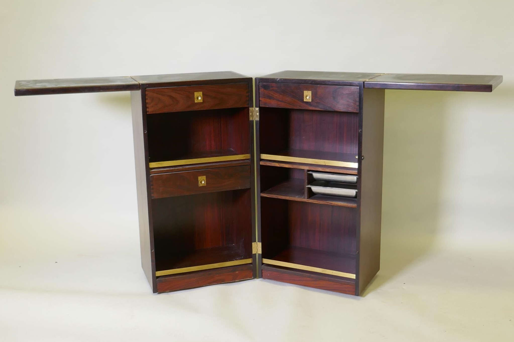 A Danish Dyrlund bar unit, with two fold out sections fitted with drawers and metal trays, and fol