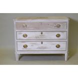An antique painted and distressed pine commode, with three long drawers, canted corners and raised
