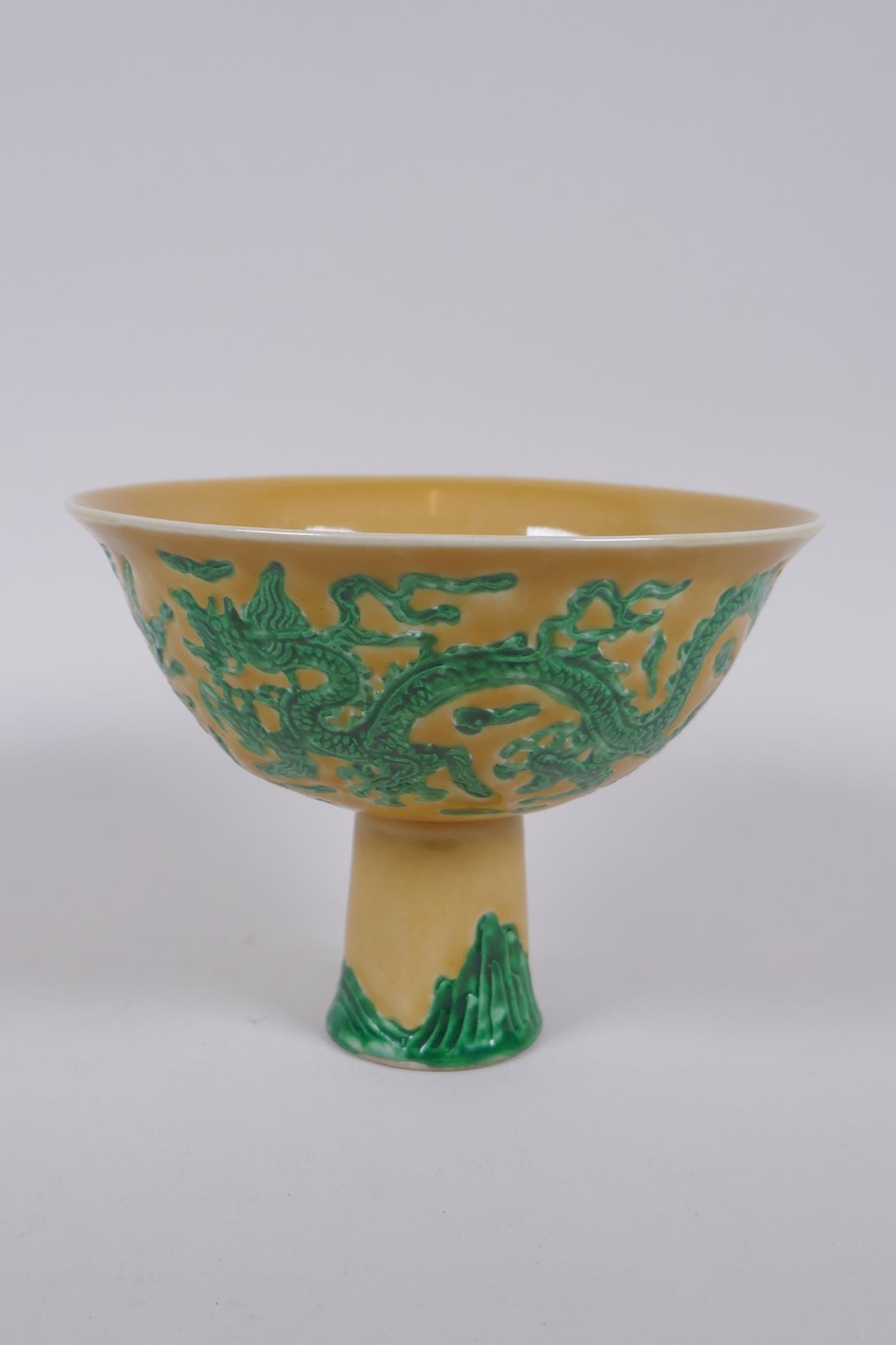 A Chinese yellow ground porcelain stem bowl with raised green enamelled dragon decoration, Xuande