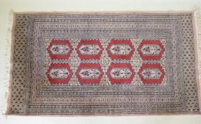A hand woven wool Bokhara rug, medallion design on a pink ground, 94 x 150cm