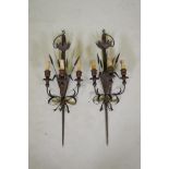 A pair of wrought iron and painted wood three branch sconces in the form of wheels and a sword hilt,