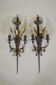 A pair of wrought iron and painted wood three branch sconces in the form of wheels and a sword hilt,