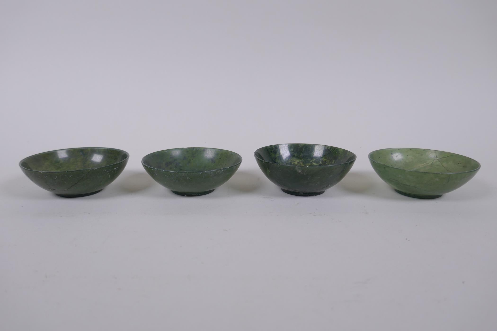 Four Chinese spinach jade bowls, AF repairs, 7cm diameter