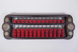 A Chinese hardwood and red stone abacus set with decorative white metal coins, 42 x 14cm