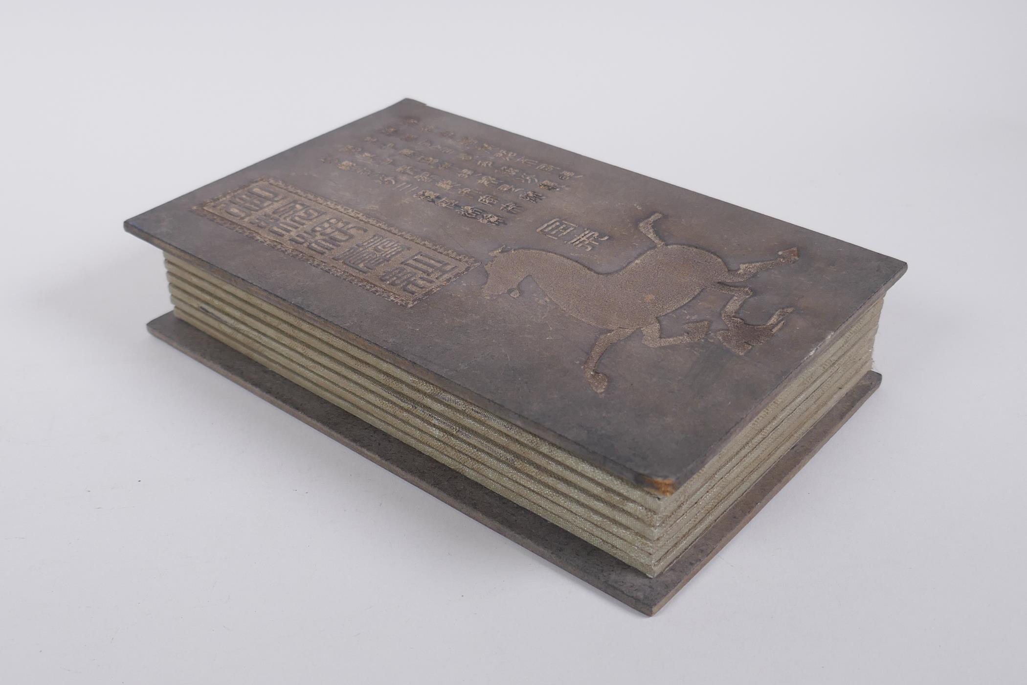 A Chinese fabric and wood bound book containing white jade tablets with chased and gilt character