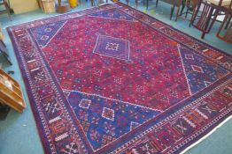 A claret and blue ground Persian Joshaghan tribal carpet with traditional medallion design,