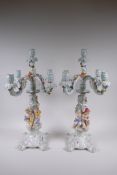 A pair of continental porcelain four branch candelabra decorated with putti, 59cm high