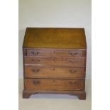 A Georgian oak fall front bureau with fitted interior over three drawers, raised on bracket supports