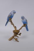 A gilt metal tea light holder in the form of a tree branch with two polychrome porcelain birds