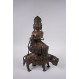 A Sino Tibetan filled gilt bronze Buddha, seated on the back of a mythical creature, 32cm high