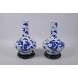 A pair of blue and white porcelain vases with dragon decoration, on carved hardwood stands,