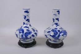 A pair of blue and white porcelain vases with dragon decoration, on carved hardwood stands,