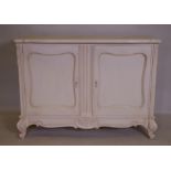 A French style painted buffet with shaped top and two cupboards, and carved decoration, raised on