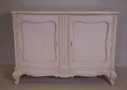 A French style painted buffet with shaped top and two cupboards, and carved decoration, raised on