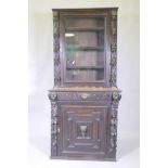 A C19th French carved oak bookcase with lion mask decoration and a glazed upper section, 84 x