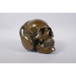 A bronzed metal ornamental skull wearing headphones, 16cm high