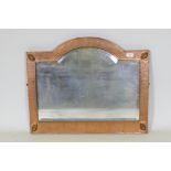 An Arts & Crafts hammered copper framed wall mirror with bevelled glass, in the manner of Liberty of