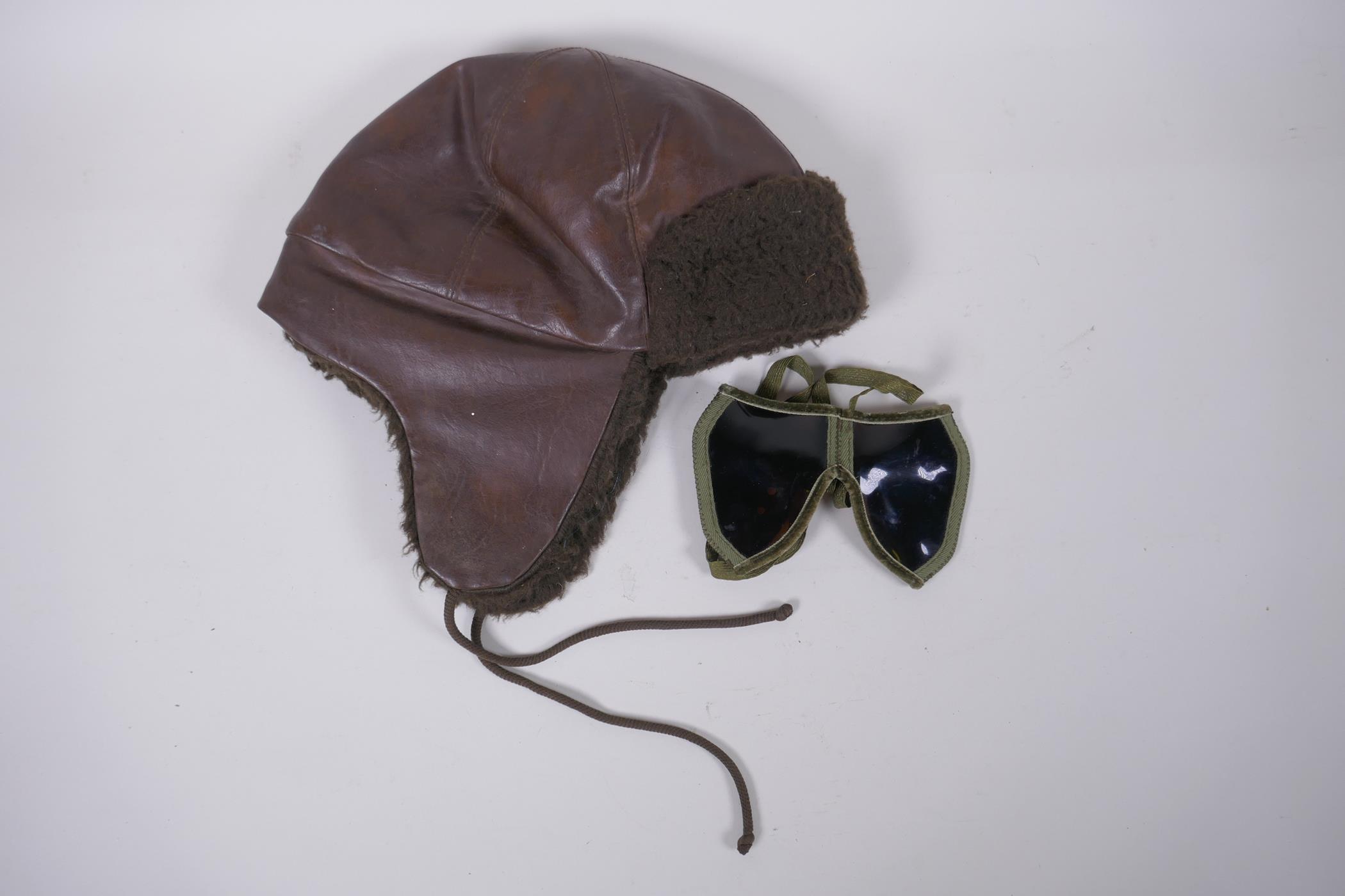 A vintage leather motoring/aviator's cap and a pair of period goggles