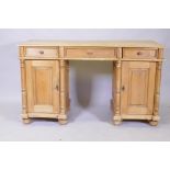 A C19th continental pine kneehole desk, with three drawers over two cupboards fitted with shelves,