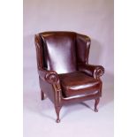 A brown leather wing back armchair, 106cm high
