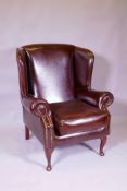 A brown leather wing back armchair, 106cm high