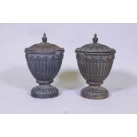 A pair of antique cast iron fluted urns and covers with mask decoration, 30cm high