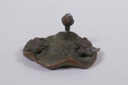 An oriental bronze incense stick holder in the form of a goldfish on a lily pad, 6cm diameter