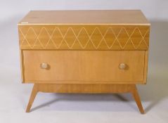 A mid century oak two drawer chest raised on splay supports, bears label, Trimline, by Tudor Rose,