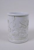 A Chinese white ground porcelain brush pot with raised decoration of water fowl on a lotus pond,