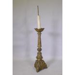 A gilt brass church torchere/pricket candlestick, decorated in relief with demons and angels,